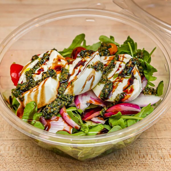 Roundabout Pizza's fresh salad with mozzarella, pesto, balsamic glaze, red onion, and cherry tomatoes.