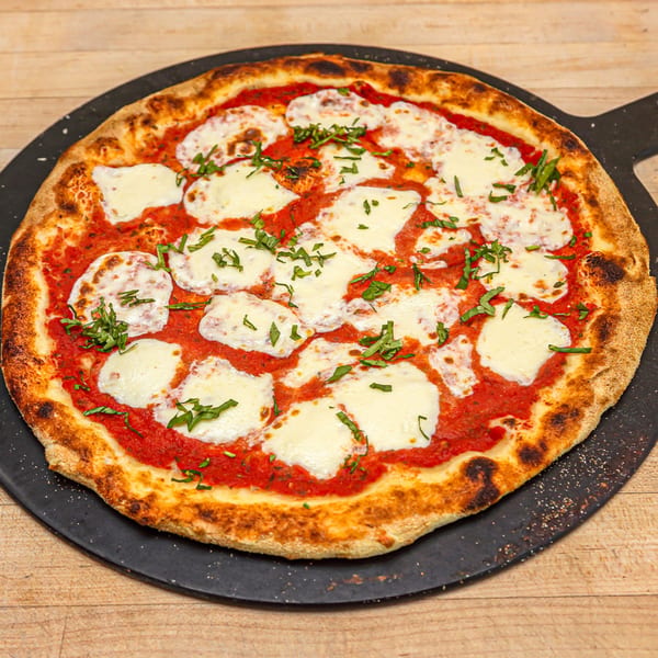 Roundabout Pizza's Margherita pizza with fresh mozzarella, red sauce, and basil on a black peel.